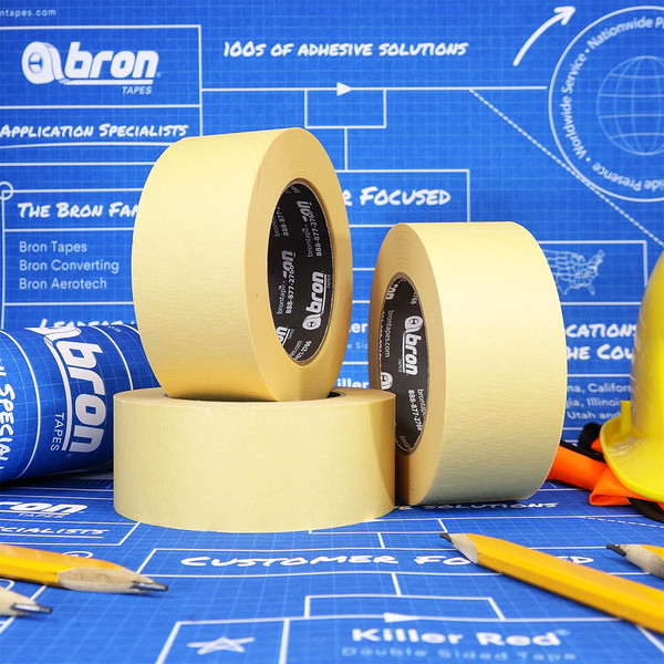 Rolls of tan masking tape on top of blue blueprints with construction pencils