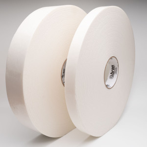 Two rolls of double sided white foam tape standing in front of silver background