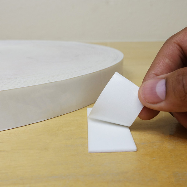 A small piece of white double sided foam tape applied to a wooden surface