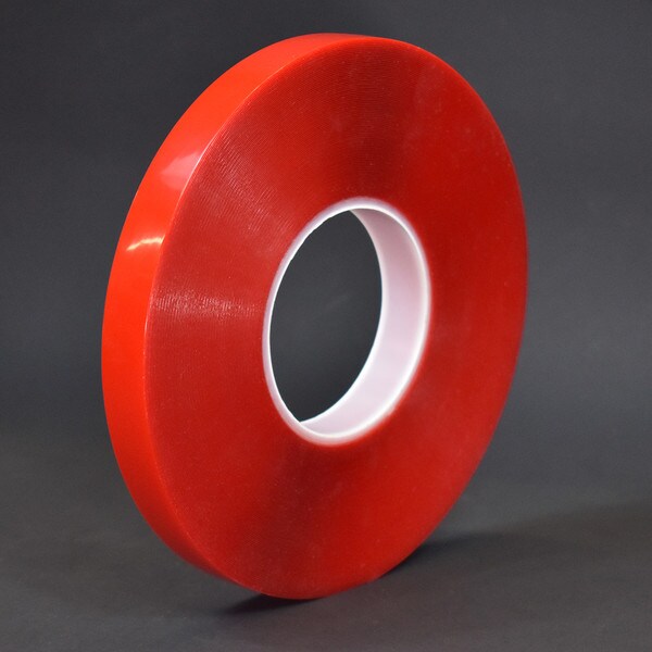 Roll of one inch clear high bond on red liner in front of black background