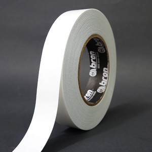 A single roll of white double sided tape slightly unwound to show paper liner