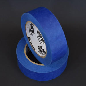 Two rolls of blue painters tape in front of black background
