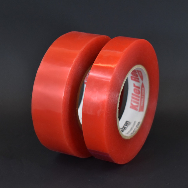 Two rolls of red liner permanent double sided tape on black background