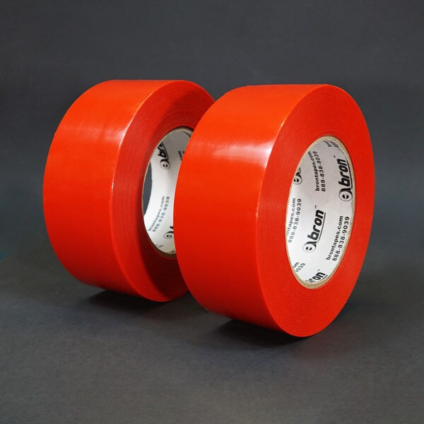 Two rolls of red polyethylene tape standing in front of grey background