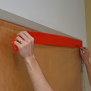 Using red polyethylene tape to create plastic containment on door