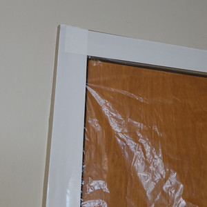 Strips of white polyethylene tape holding plastic sheeting over a door