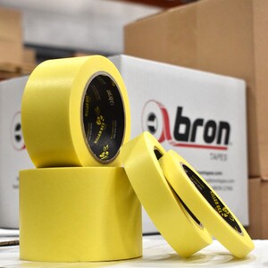 Rolls of yellow masking tape in various sizes sitting on cardboard box