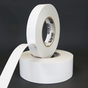 Two rolls of double sided tissue tape with the top roll slightly unwound to show carrier and adhesive