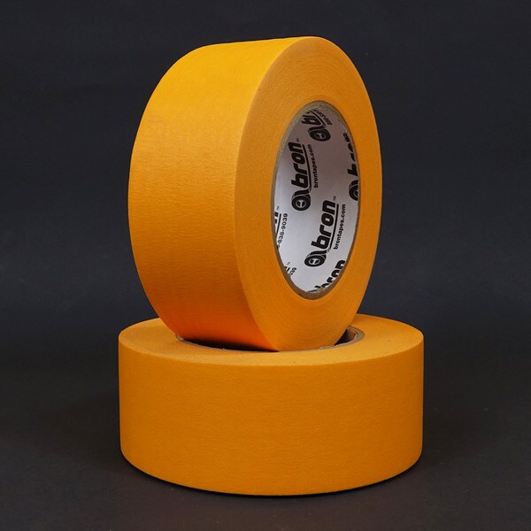 Two rolls of orange high temperature masking tape stacked on black background