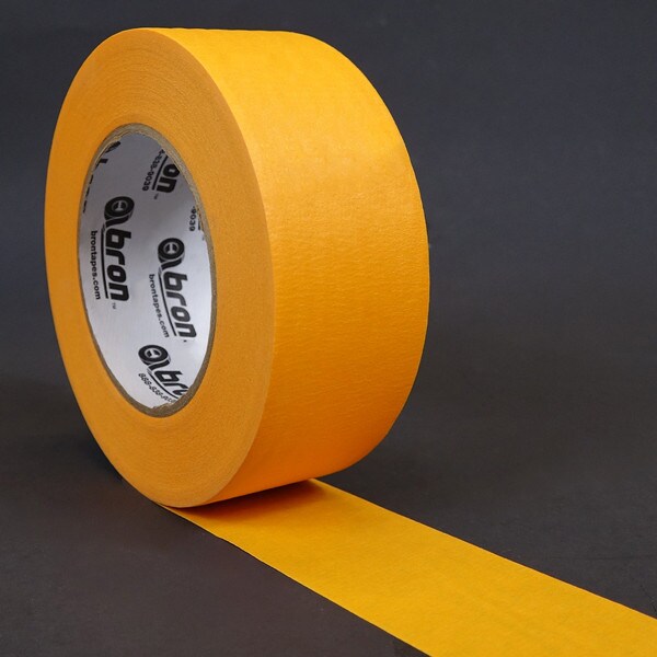 Roll of orange masking tape unwound on black background