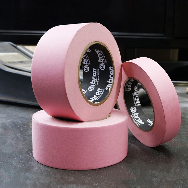 Three rolls of pink masking tape stacked in an industrial setting